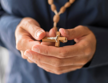 manos de hombre sujetando el santo rosario