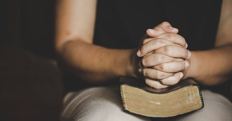 Persona postrada en la oración